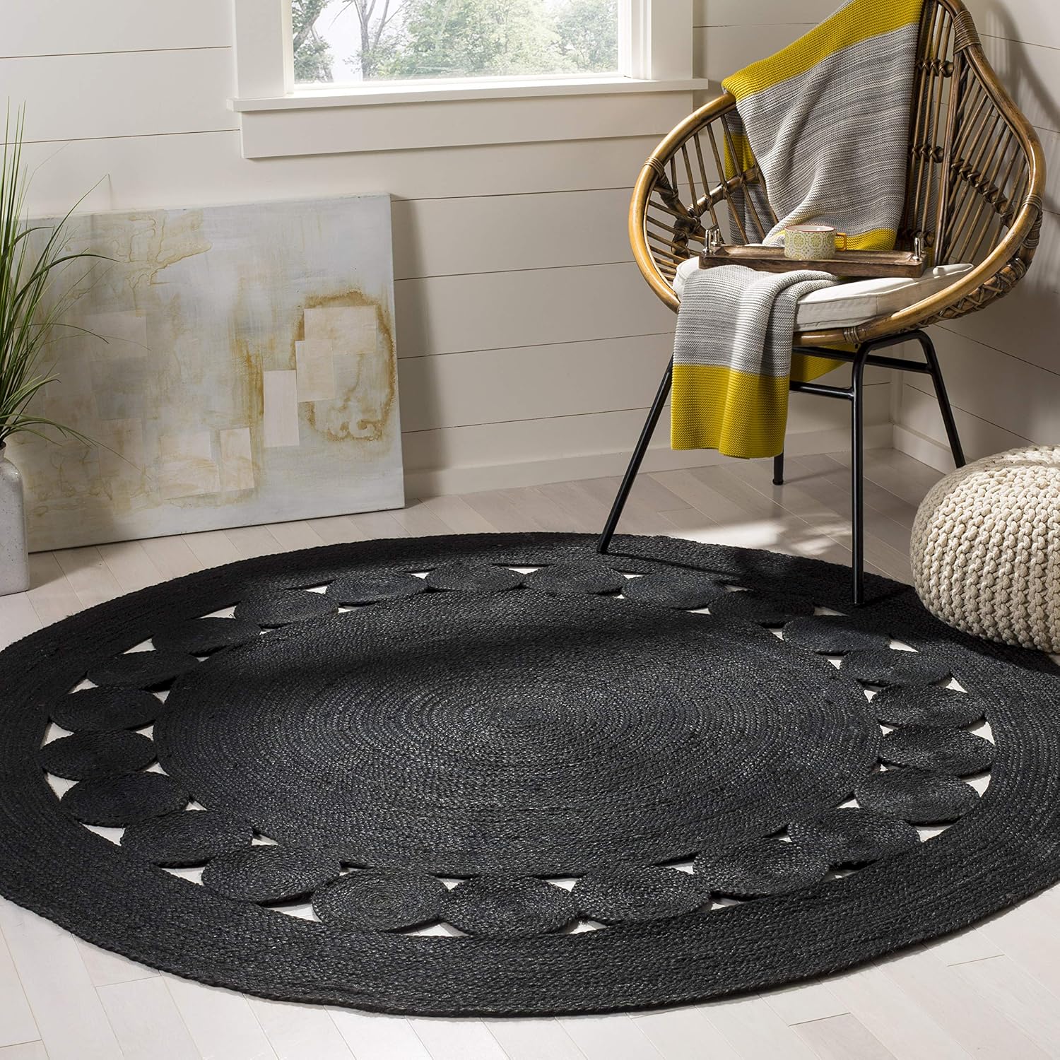 Blackroundarearug_9876a468-3570-4a41-b965-d96804d25d54.jpg Black jute rug with decorative circle border, rattan chair, and neutral decor in a bright room.