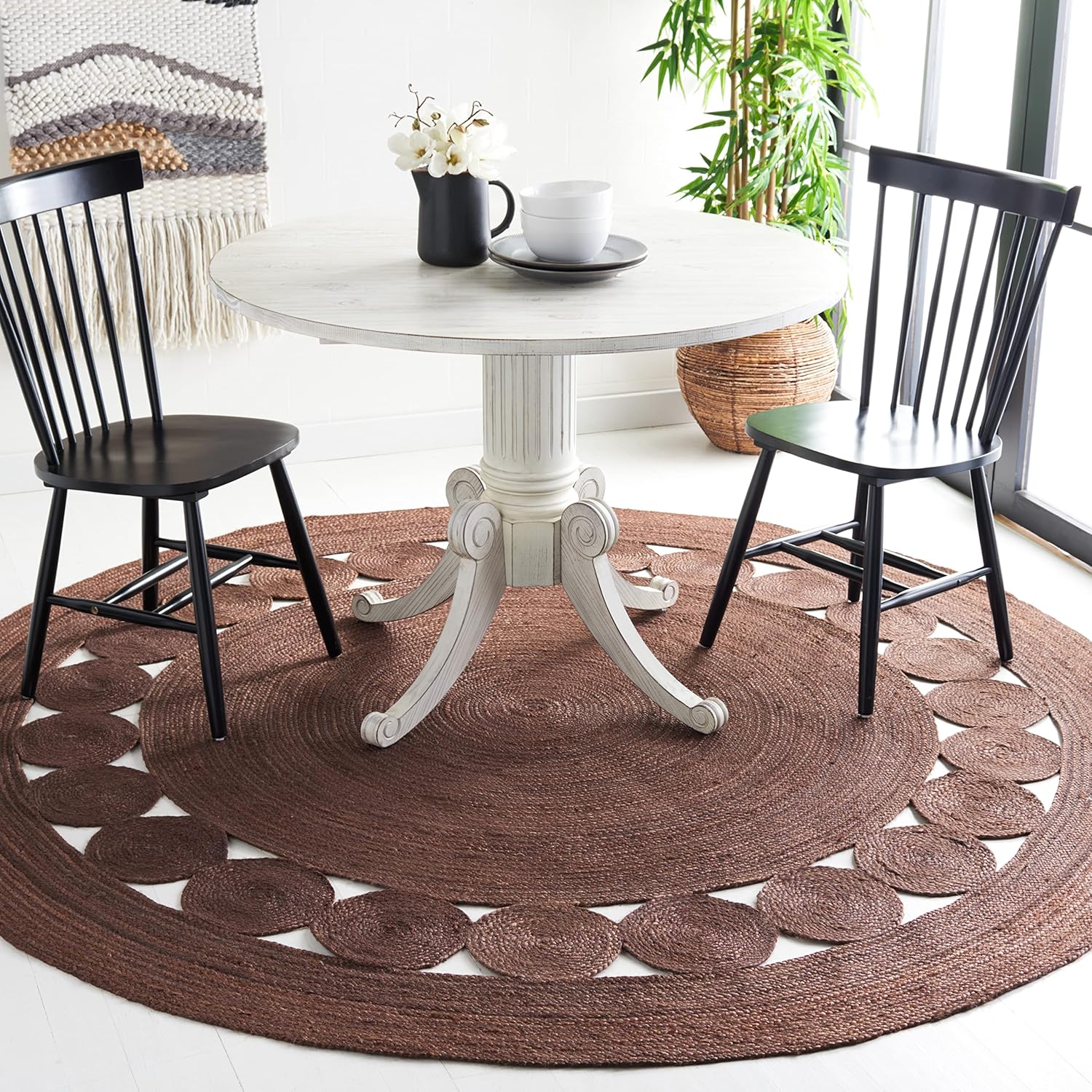 BrownRoundrug.jpg Round dining table with black chairs on a brown jute rug. Interior design featuring natural textures and light wood.