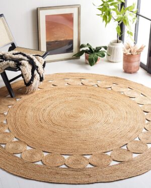 Round jute rug with a circular pattern, next to a chair, potted plants, and a framed picture