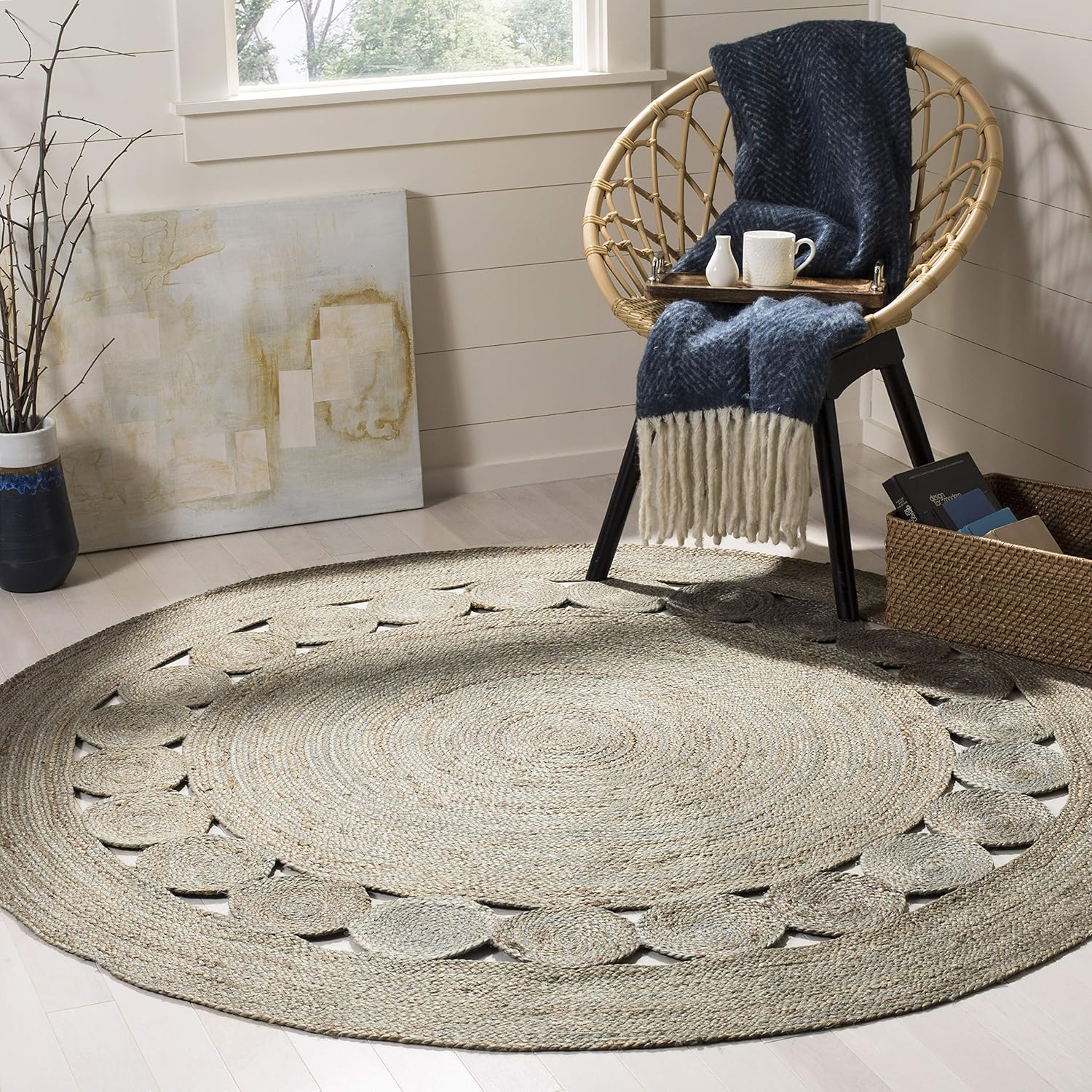 greyjuteroundrugtikki.jpg Round jute rug under a wicker chair with a blue throw and decor, creating a cozy interior scene.