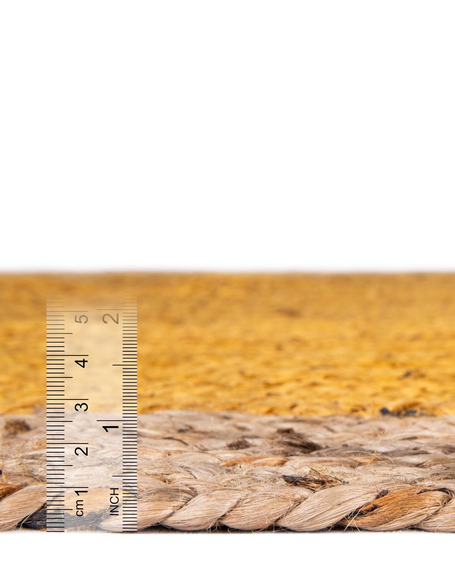 Yellow Center Jute Rug Close-up shows the edge of a jute rug with a yellow center, viewed with a ruler to indicate centimeter measurements.