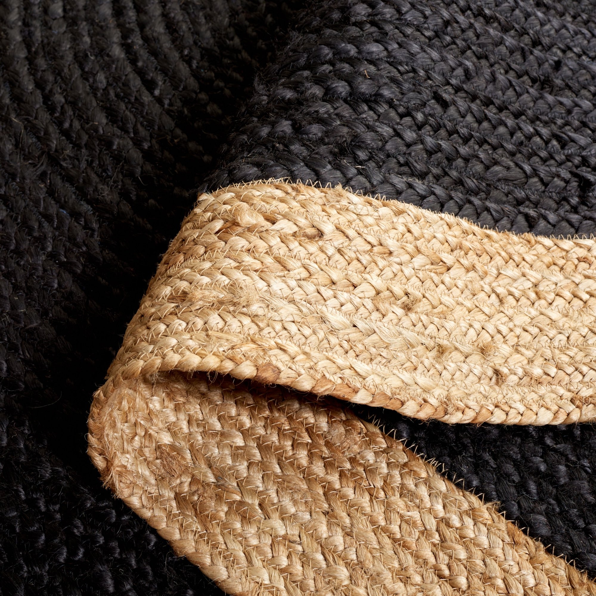 Black Jute Rug with Braided Border Close-up shows black jute area rug with a natural braided border that is folded over.